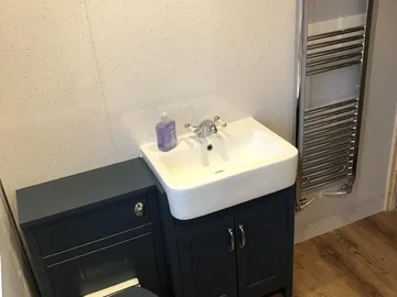 A navy vanity unit and toilet with a chrome towel rail, fitted by Quick Response
