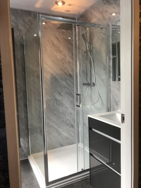 A shower enclosure with marble-effect wall panels and a rainfall shower
